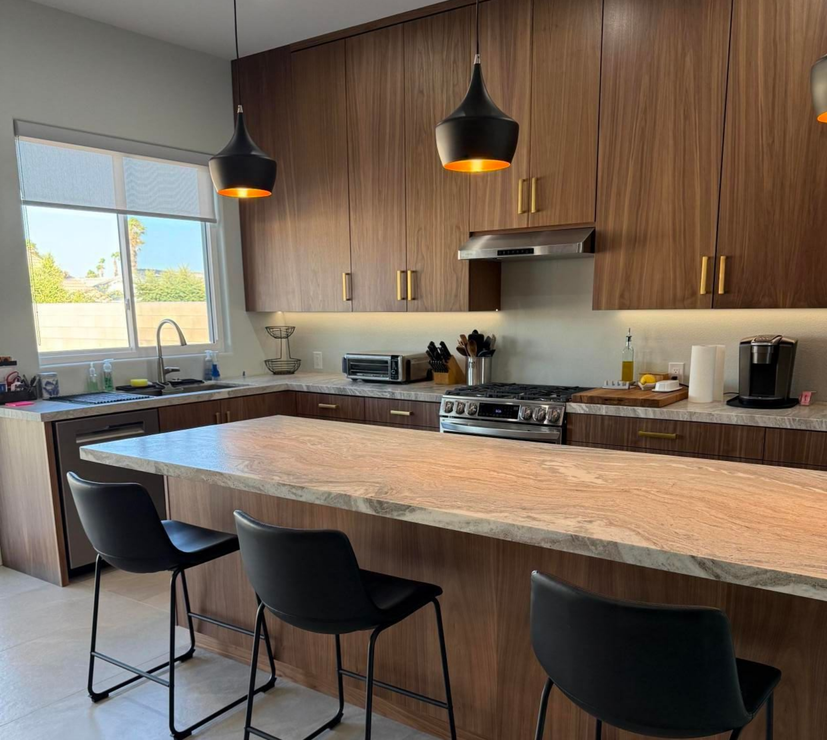 Bright open-plan kitchen and living room with white cabinets, island, light wood floors, and large windows