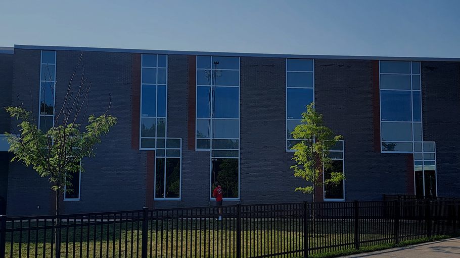 A large brick building with lots of windows is behind a fence in Upper Arlington
