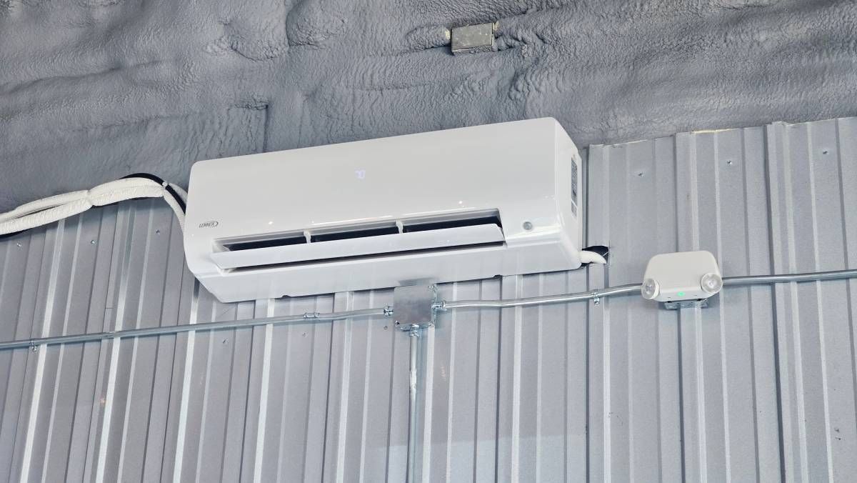 White wall-mounted air conditioner above sheer curtains on a gray wall