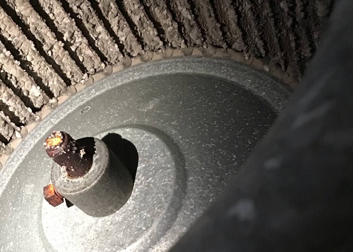 Close-up of a metal fan with a rusty center post on a striped fabric surface