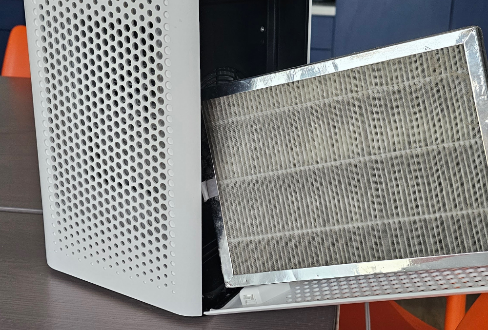 Open white vented panel with a gray filter screen leaning against it.