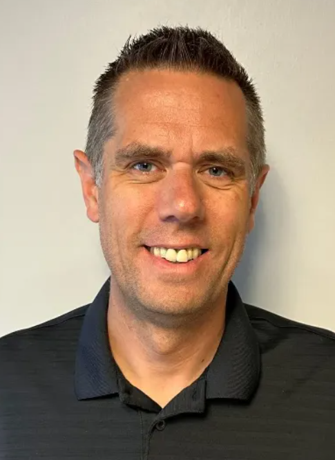 A man in a black shirt is smiling for the camera.