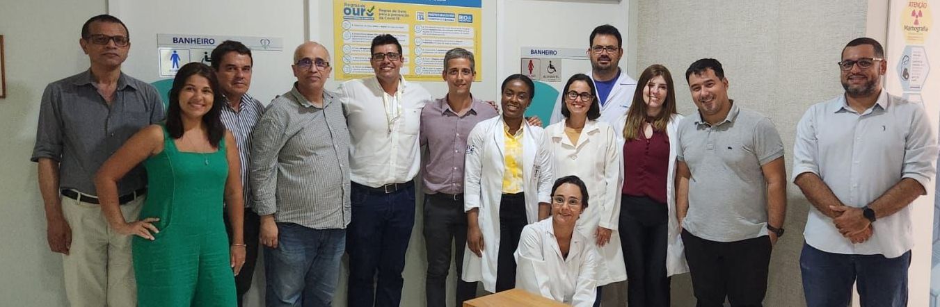 Grupo de pessoas posando juntas, provavelmente em um ambiente médico. Elas estão sorrindo.