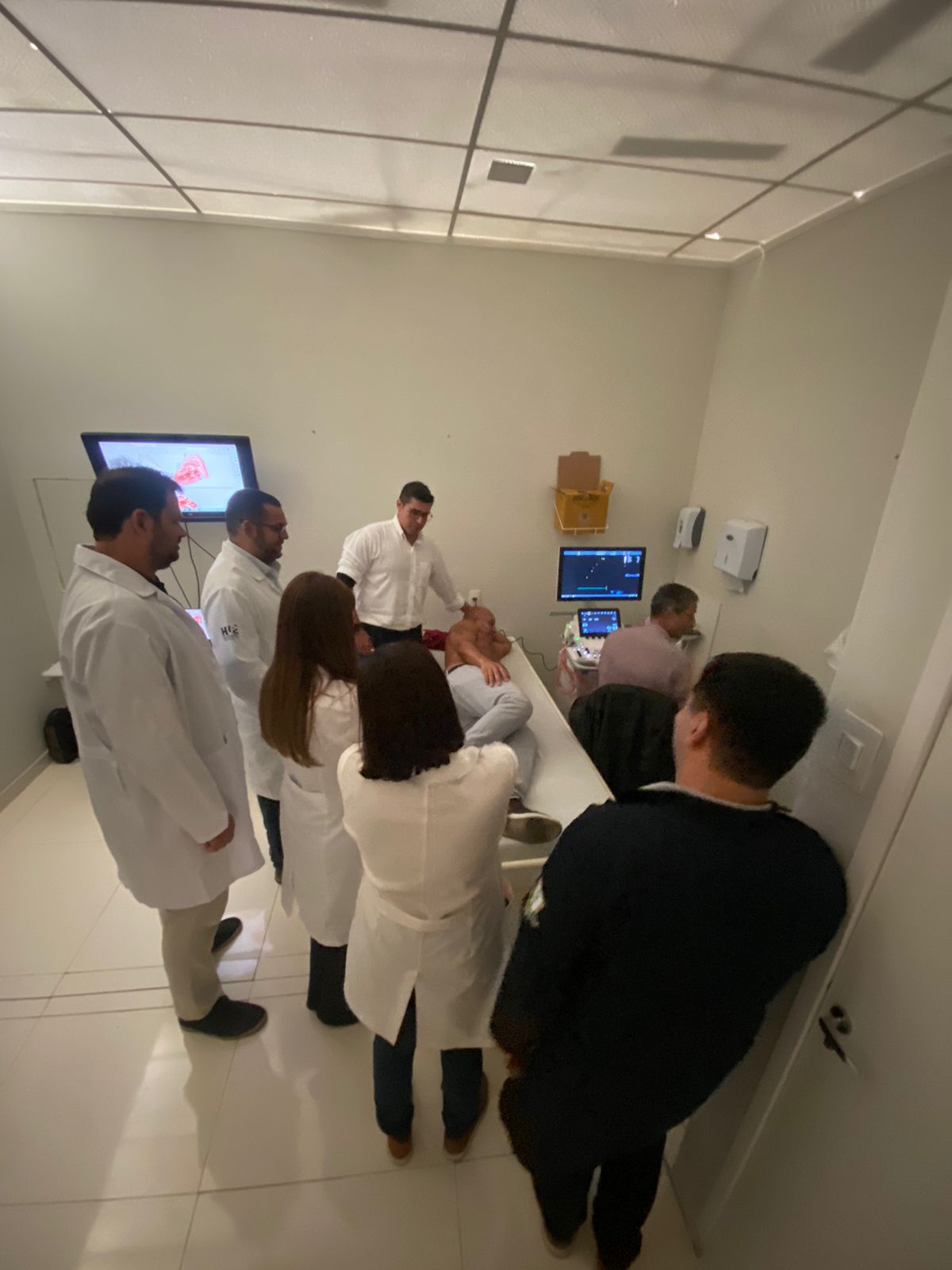 Equipe médica observando um paciente durante um exame de ultrassom em ambiente clínico.