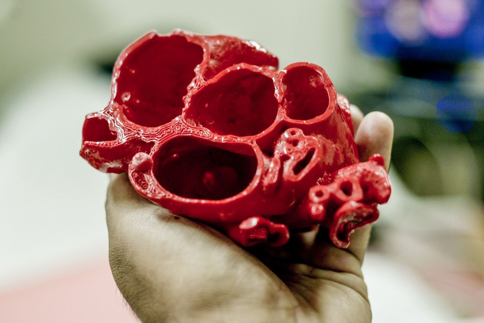 Modelo de coração vermelho impresso em 3D, segurado na mão de uma pessoa.