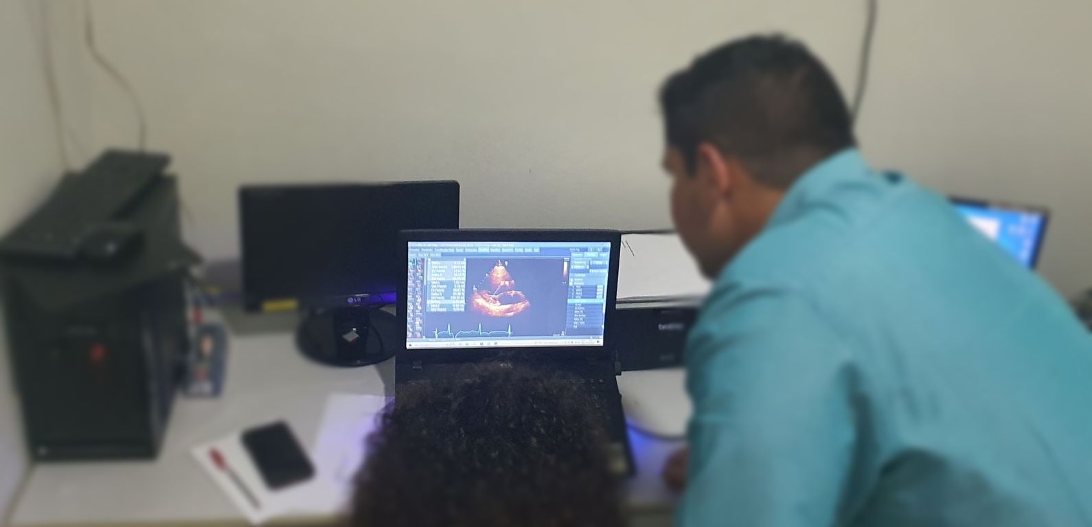 Uma pessoa observa um laptop exibindo uma imagem médica em um ambiente de escritório.