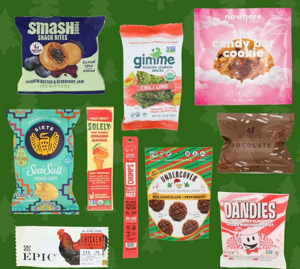 Assorted colorful snack and candy packages arranged on a green background.