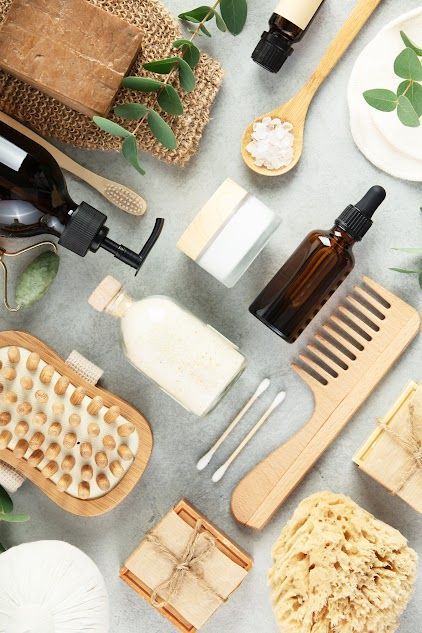 Assorted natural bath and hair care items with brushes, combs, soaps, and amber bottles on a light surface