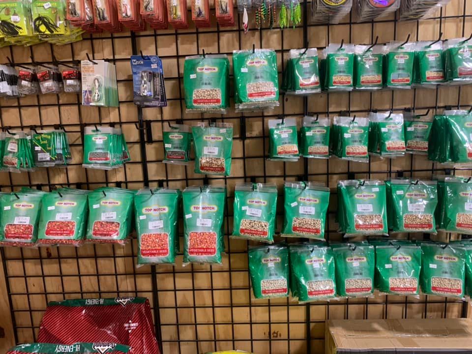 Green packaged goods hanging on a store display rack with rows of products in a market aisle