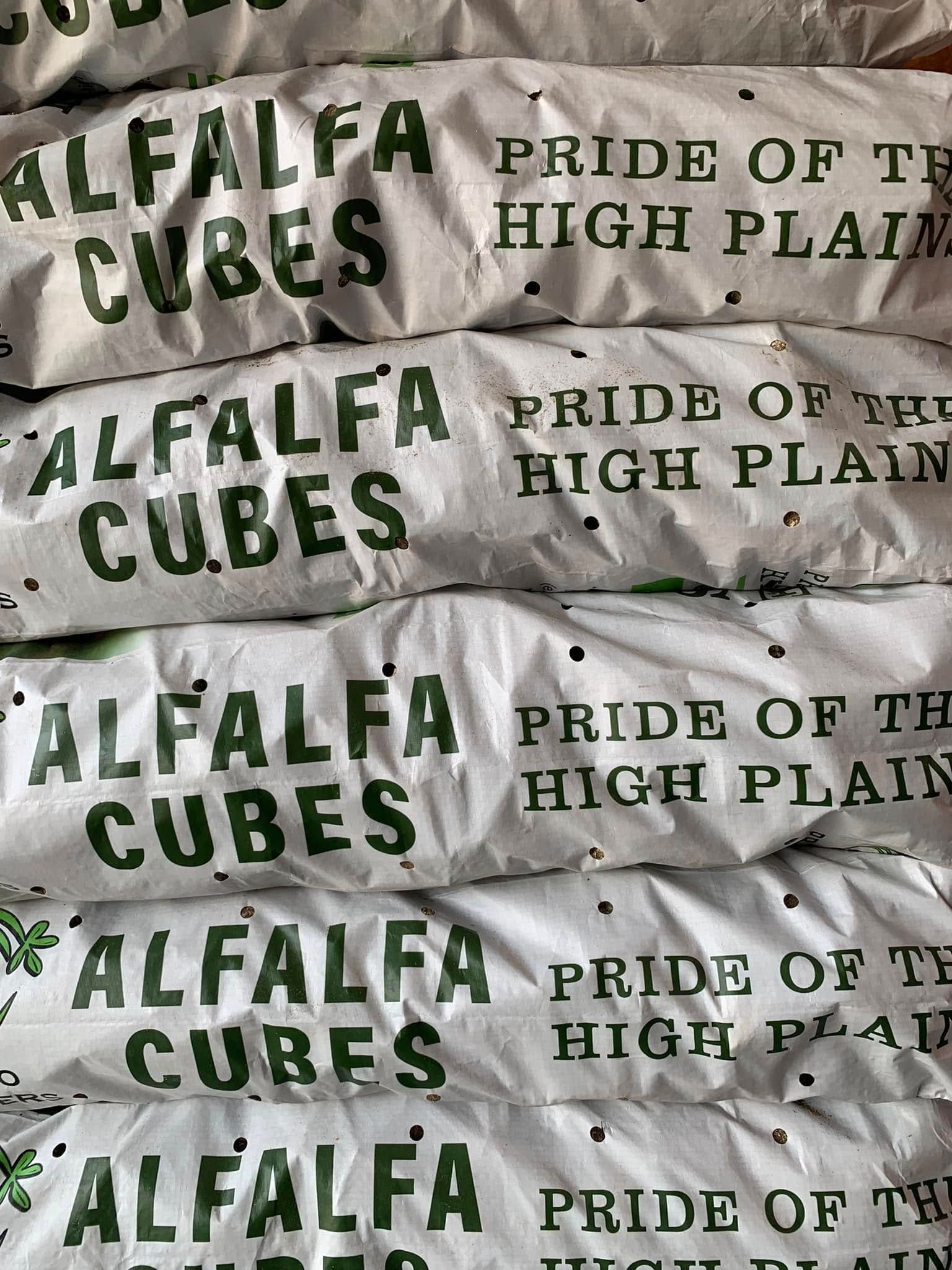 Stacked bags of Alfalfa Cubes feed labeled “Pride of the High Plains”