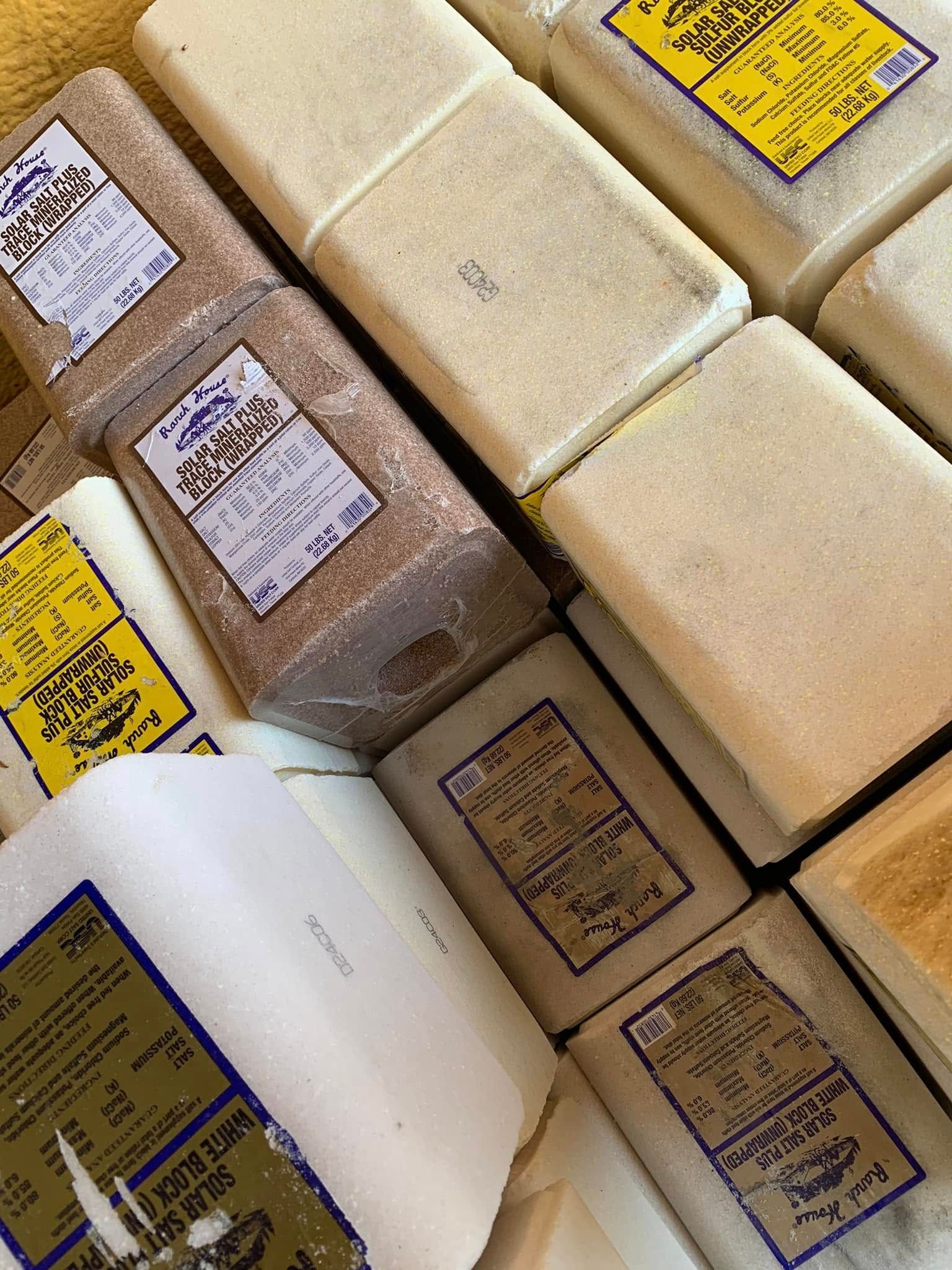 Stack of wrapped soap bars in cream, white, and brown packaging with handwritten labels.