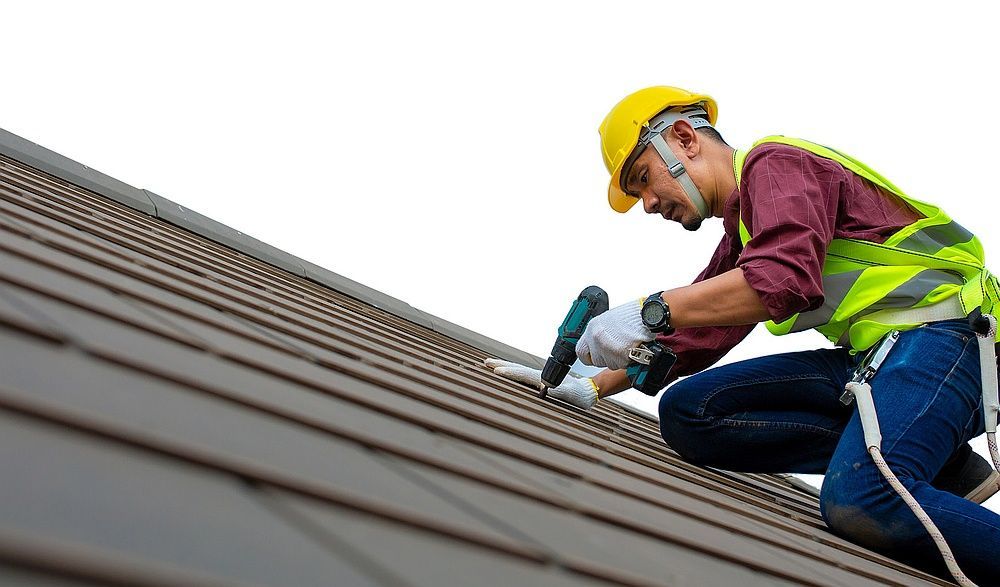 Worker in yellow hard hat and safety vest using a power tool on a sloped roof