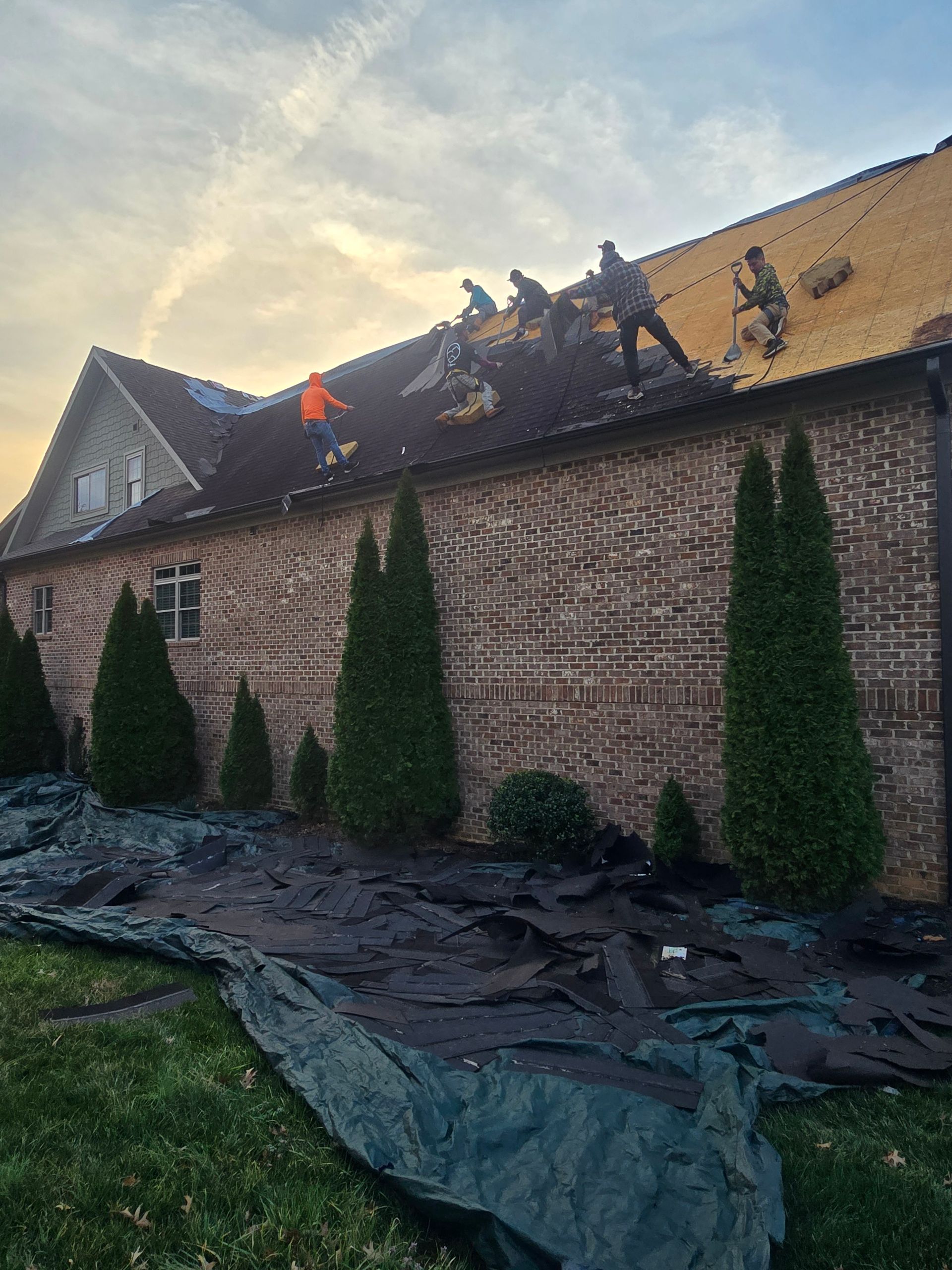 Aerial view of a dark gray house with a tiled roof and surrounding yard during construction