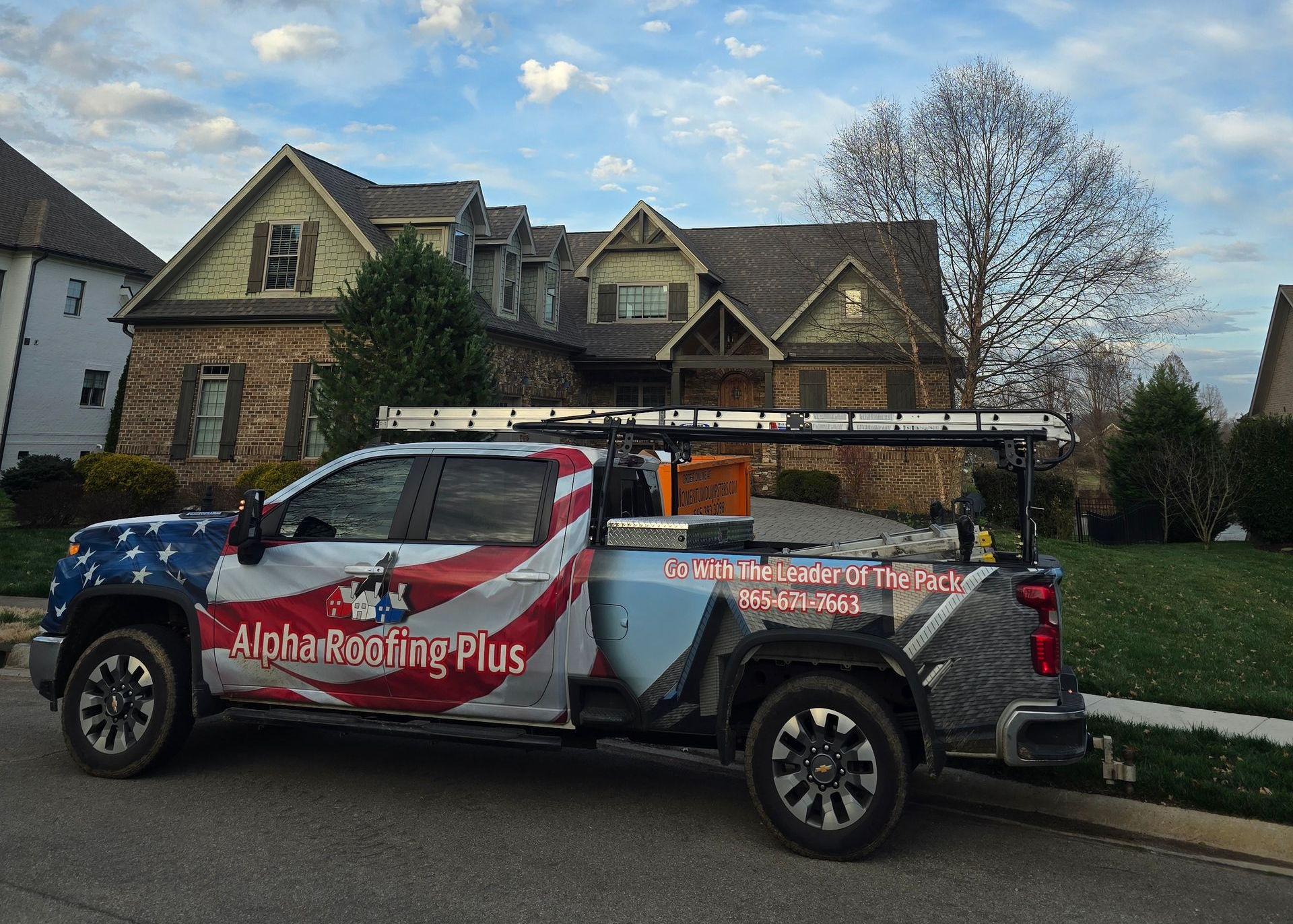 Blue pickup truck and trailer with American flag graphics parked in a driveway beside a house. Blue pickup truck and trailer with American flag graphics parked in a driveway beside a house.