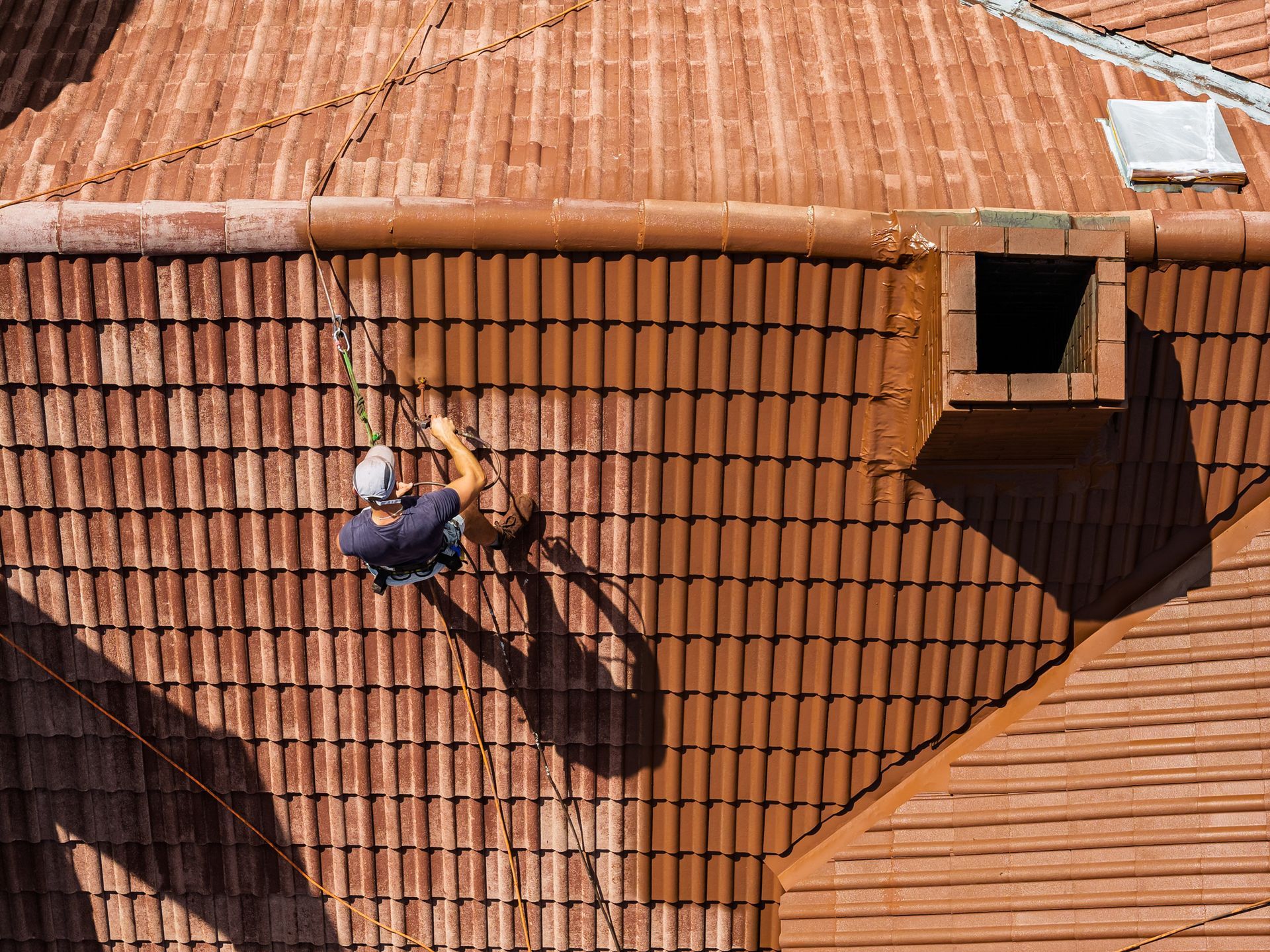 Roofing crew nailing down new shingles on a steep home roof.