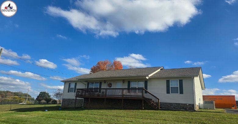 Single-story house with front porch, gray siding, and a grassy yard under a blue sky