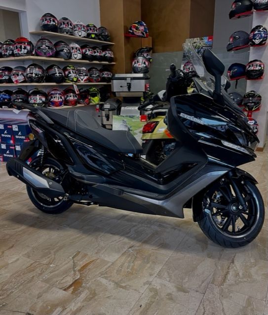 Uno scooter nero in un negozio, con caschi sugli scaffali sullo sfondo.