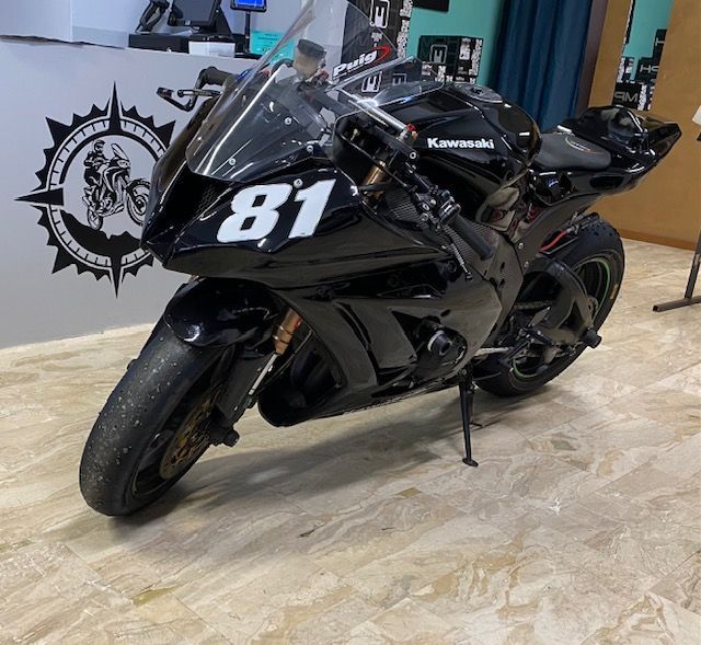 Moto sportiva Kawasaki nera con numero 81 parcheggiata al chiuso.