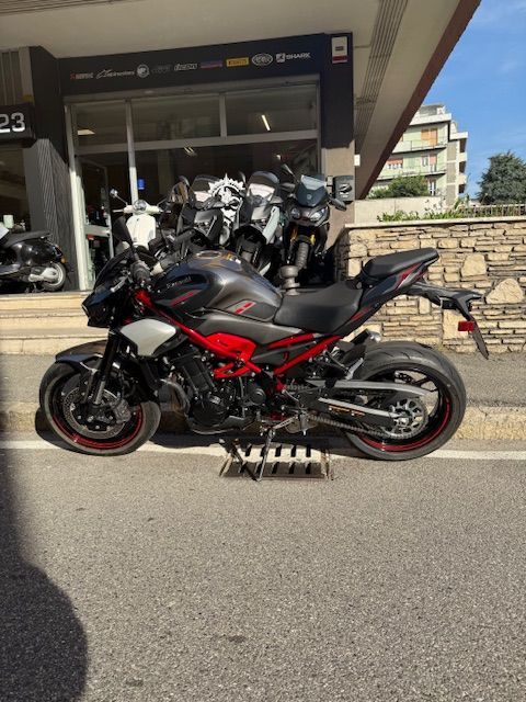 Una motocicletta Kawasaki Z900 grigia e rossa parcheggiata fuori da un negozio.