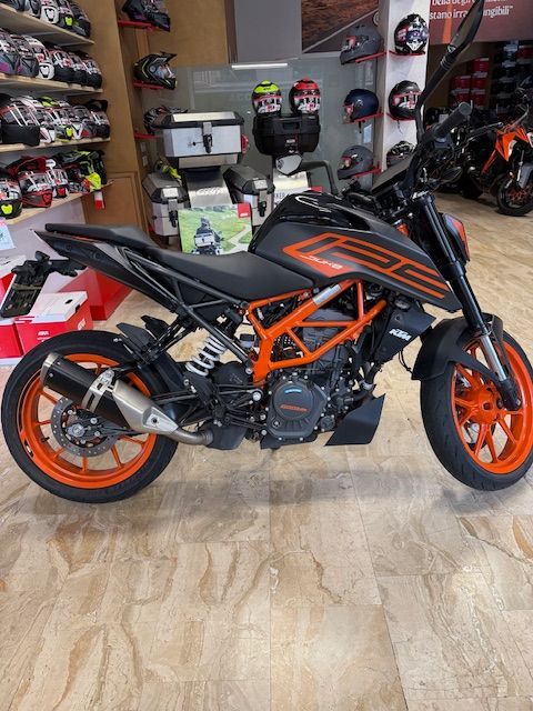 Motocicletta KTM 250 Duke nera e arancione in un'officina, ruote, telaio e dettagli arancioni.