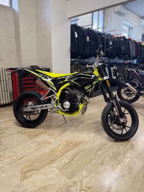 Motocicletta SWM nera e gialla in un'officina, vista angolata.
