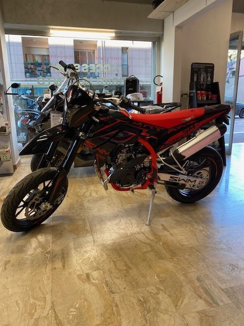 Motocicletta Beta nera e rossa parcheggiata al chiuso, con sella rossa e scarico argentato.