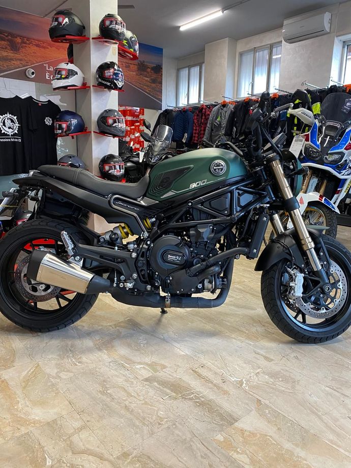 Motocicletta Benelli verde in uno showroom con caschi e abbigliamento in esposizione.