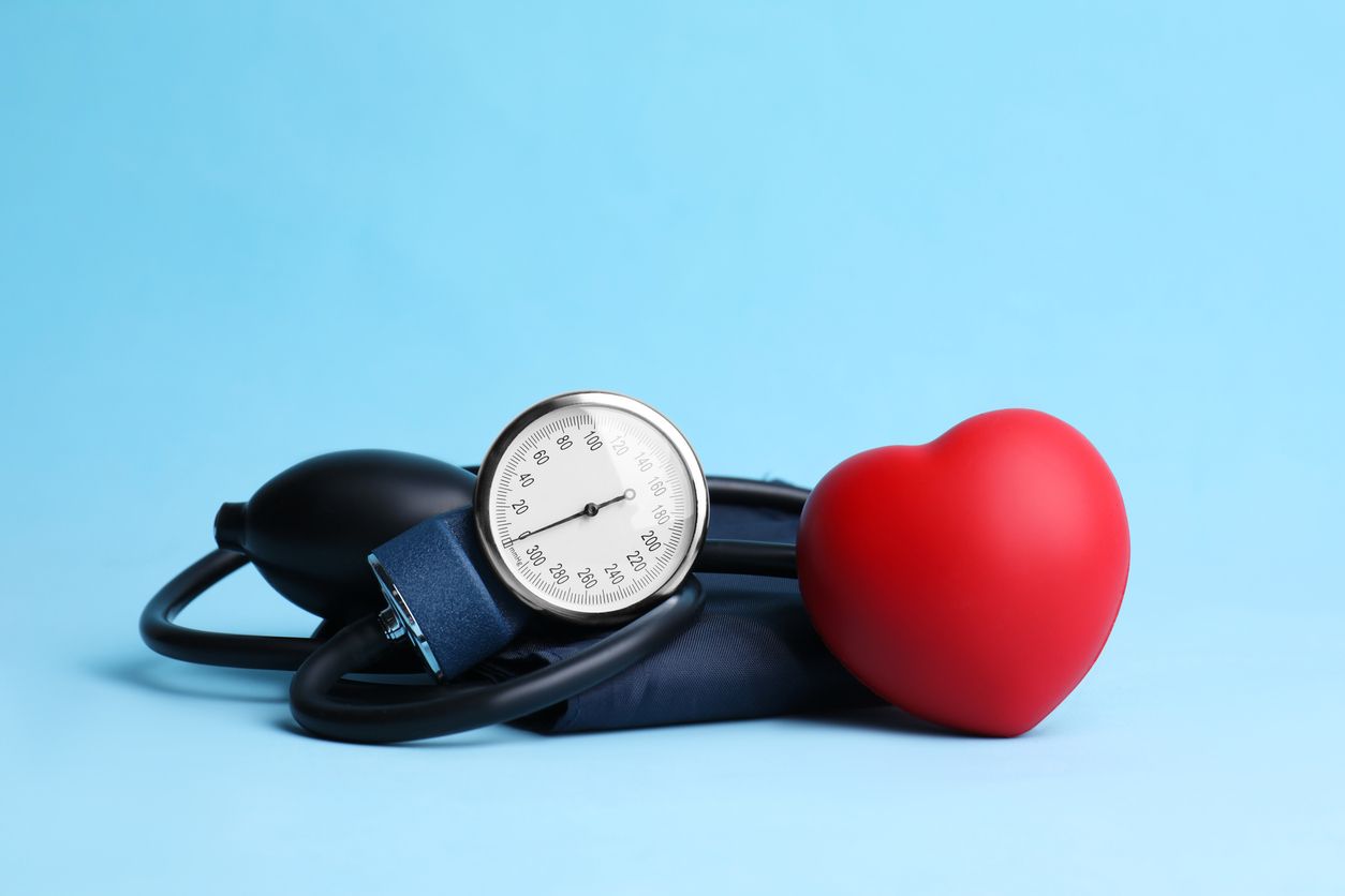 Blood pressure cuff with gauge beside a red heart on a blue background