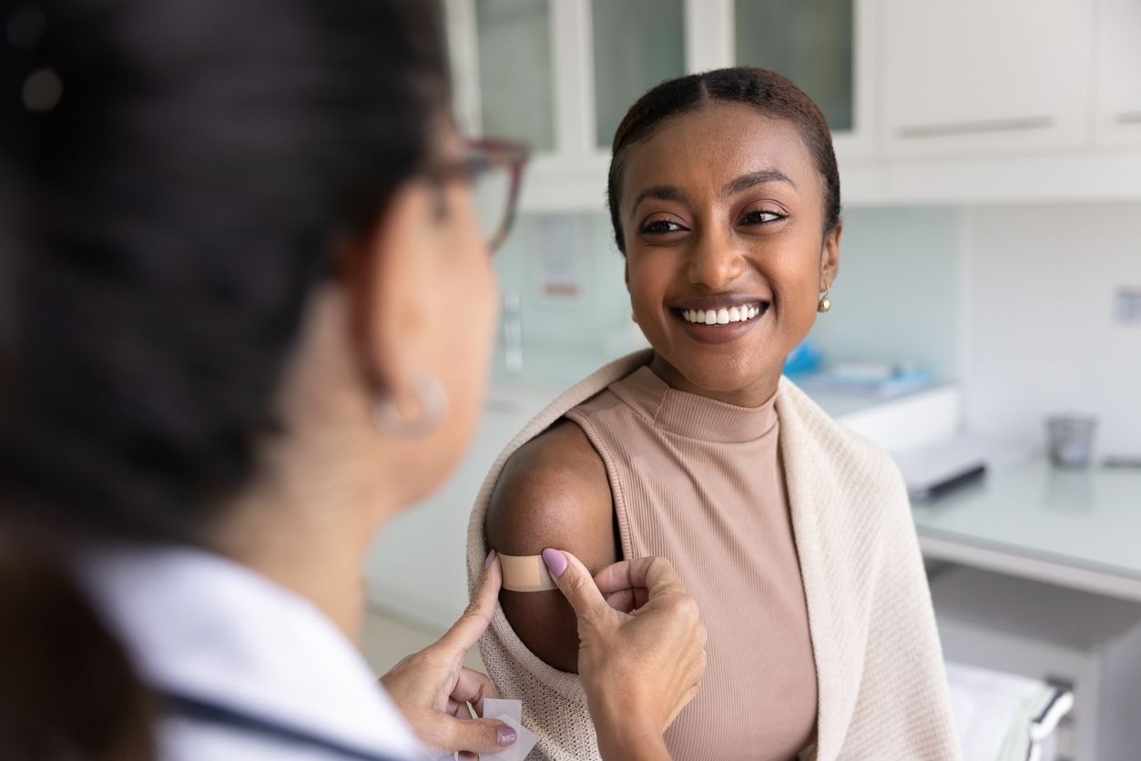 Doctor giving a vaccine shot to a smiling patient in a bright clinic