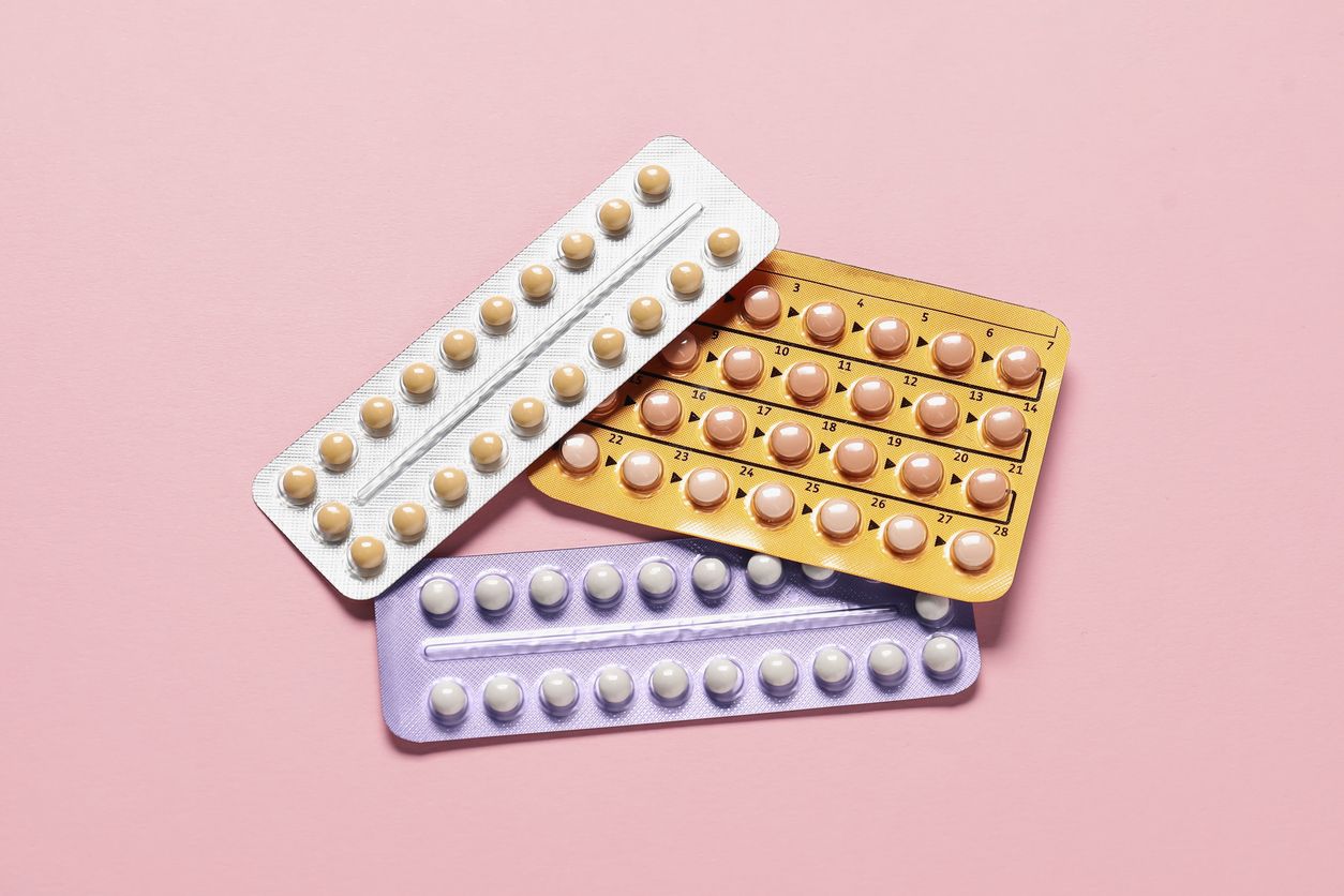 Three blister packs of pills on a pink background