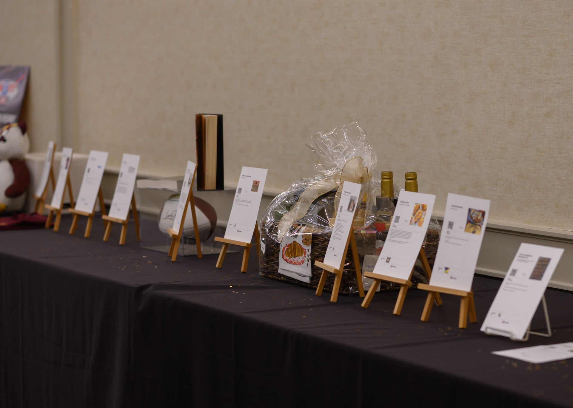 Display table with framed certificates and gift baskets arranged on a black tablecloth at an indoor event