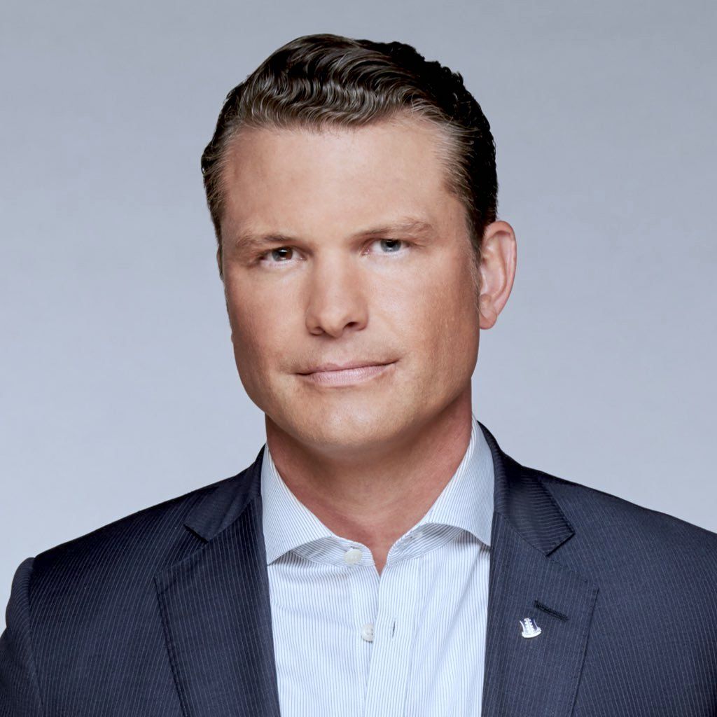 Studio portrait of a man in a dark suit and light blue shirt on a gray background
