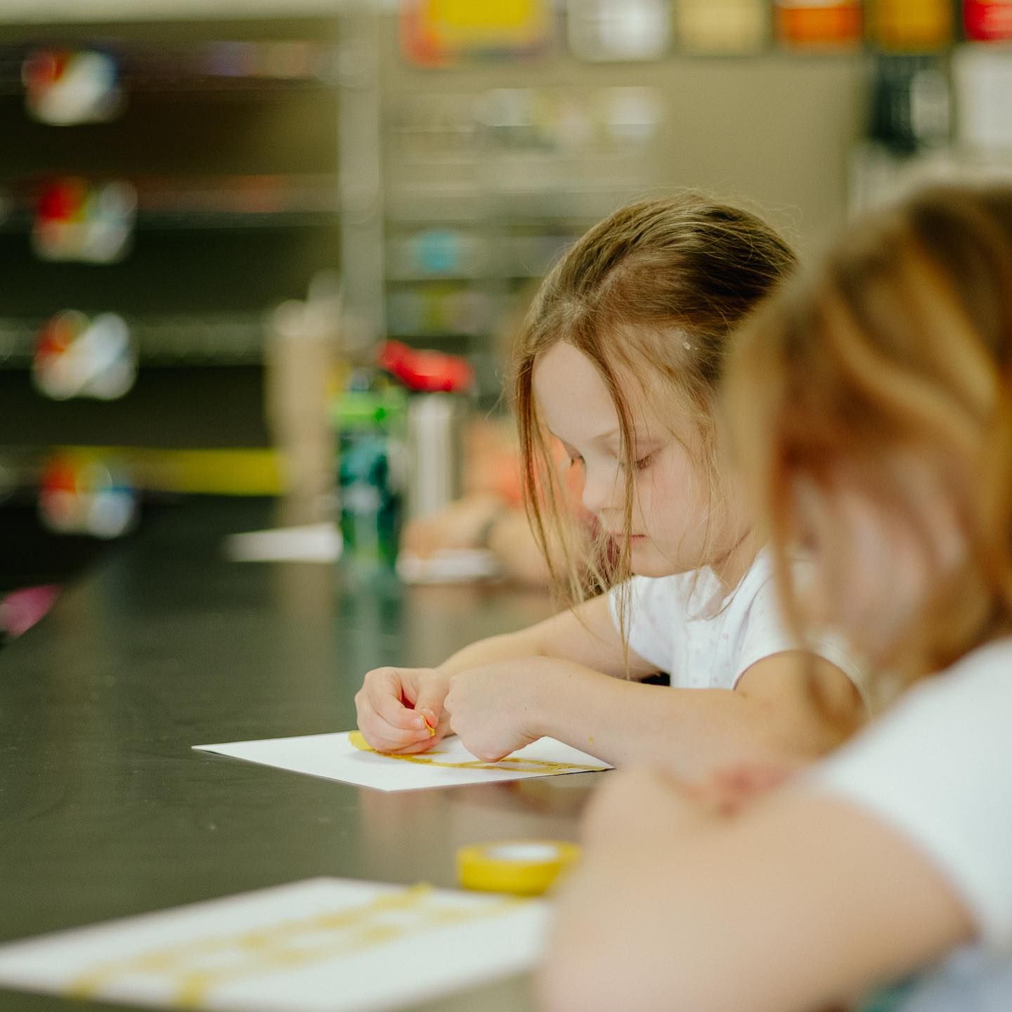 Children drawing with crayons at a table in a classroom
