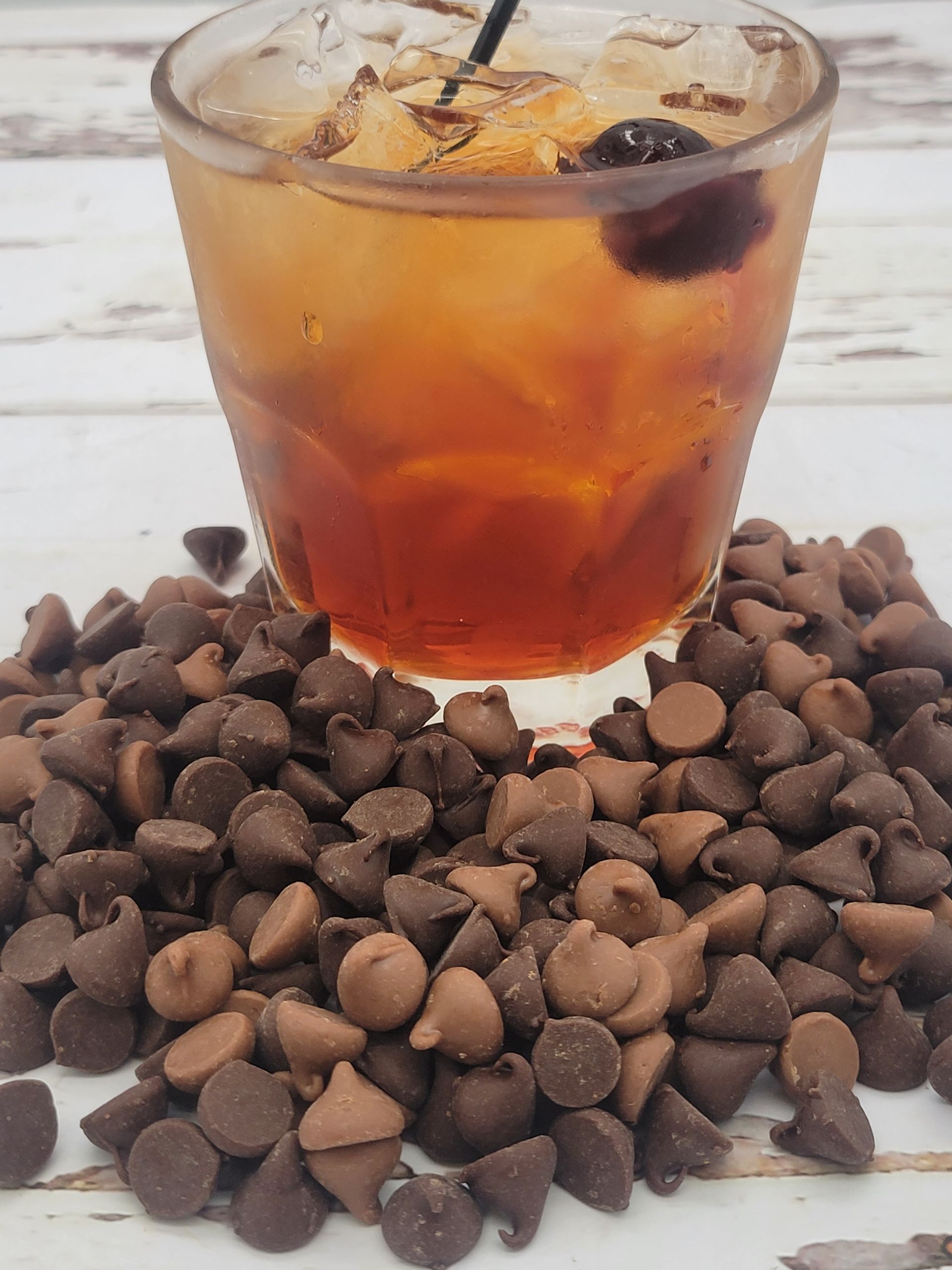A glass of alcohol is sitting on top of a pile of chocolate chips.