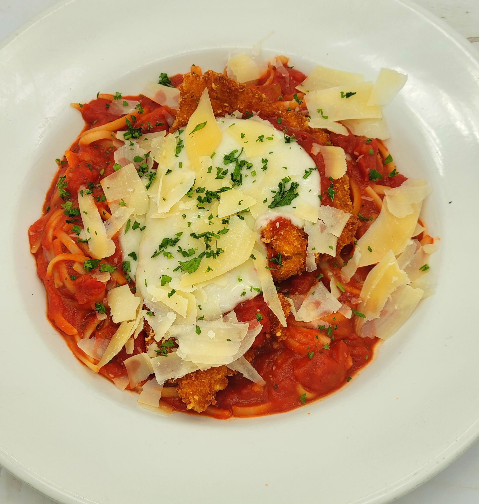A close up of a plate of food with noodles, tomato sauce and cheese
