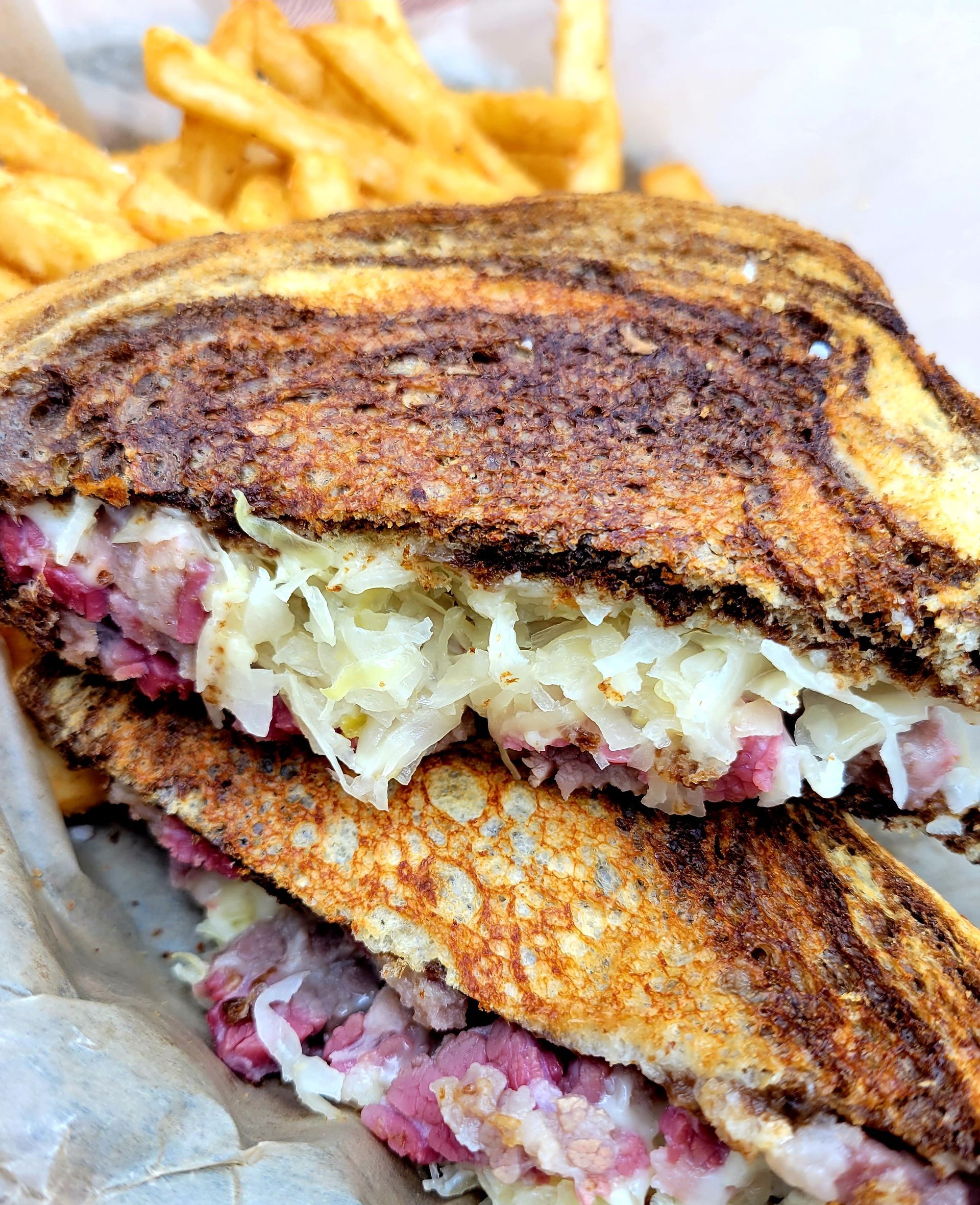 A close up of a sandwich with meat and sauerkraut.