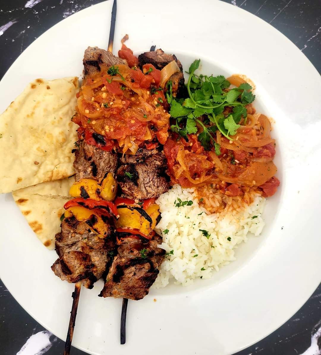 A white plate topped with meat rice and vegetables