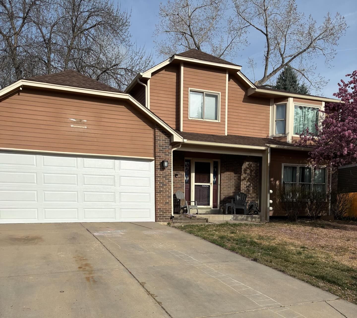 Suburban two-story brick house with a white garage and a driveway in front.