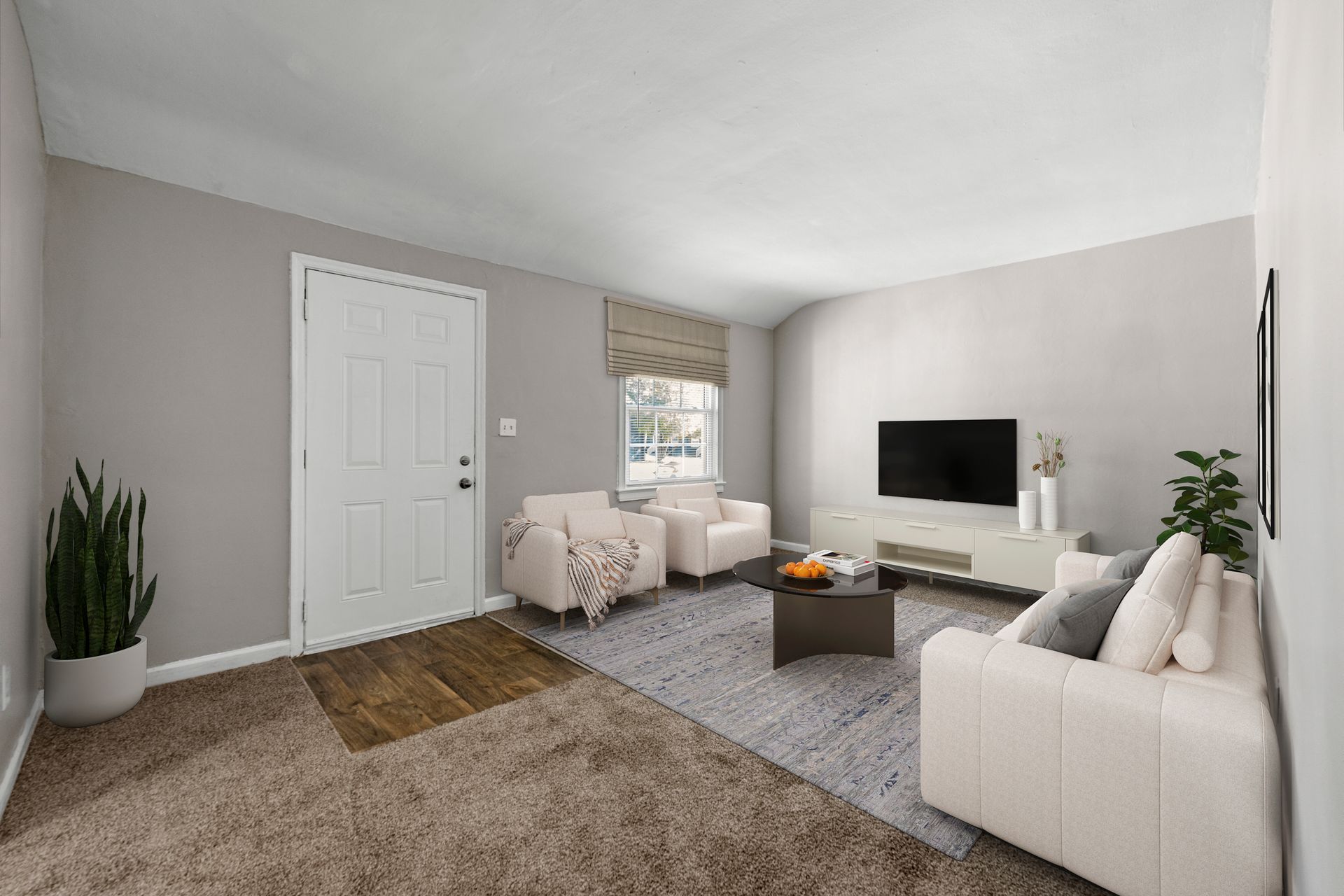 Bright living room with beige sofa, TV, plants, and window seating on gray walls and carpet