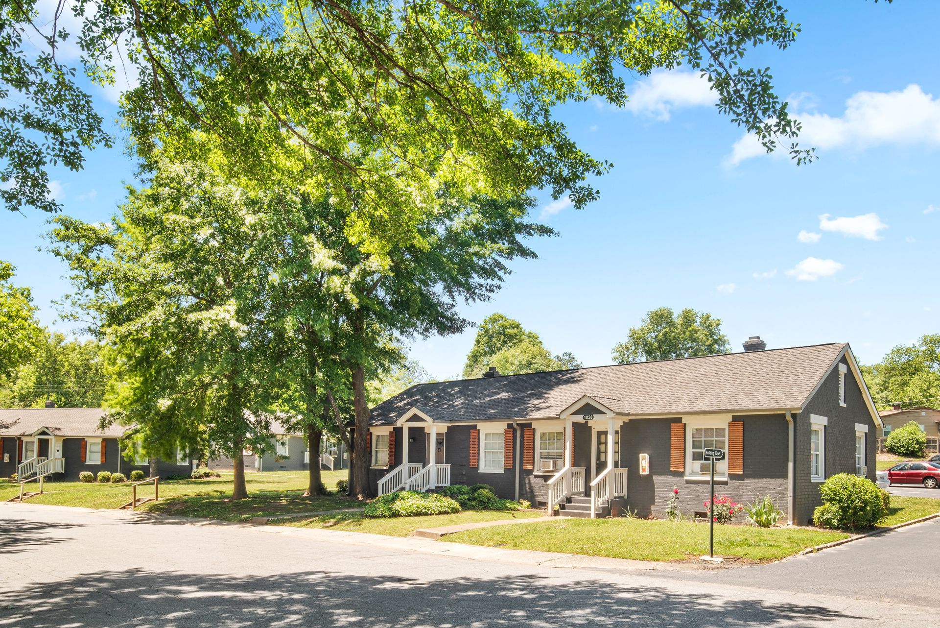 Single-story brick homes on a sunny tree-lined residential street