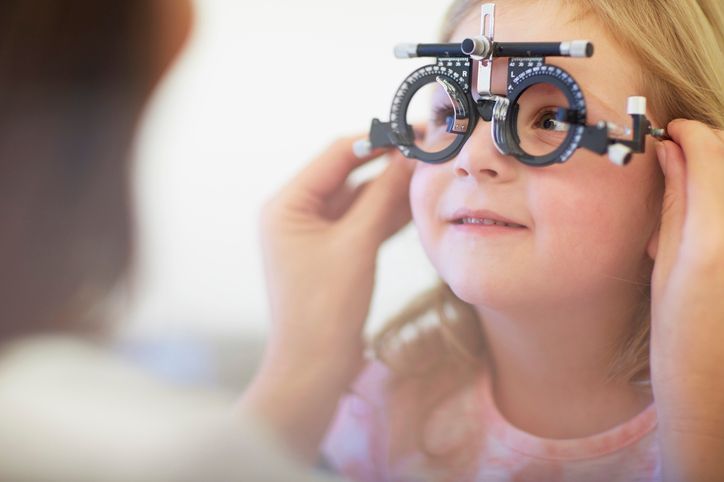 Una bambina indossa un forottero e si sottopone a un esame della vista. Il medico regola il dispositivo.