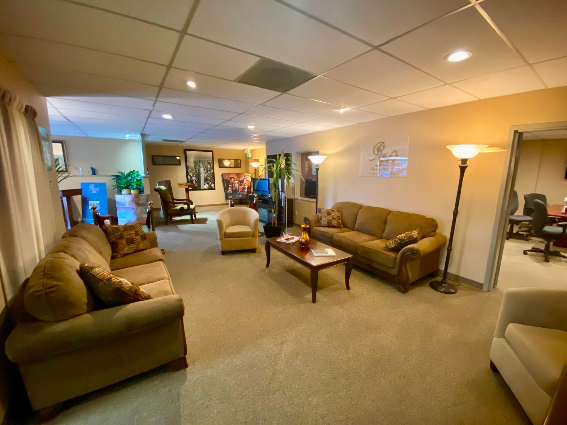 Spacious lounge with sofas, chairs, coffee table, and floor lamp under recessed ceiling lights.