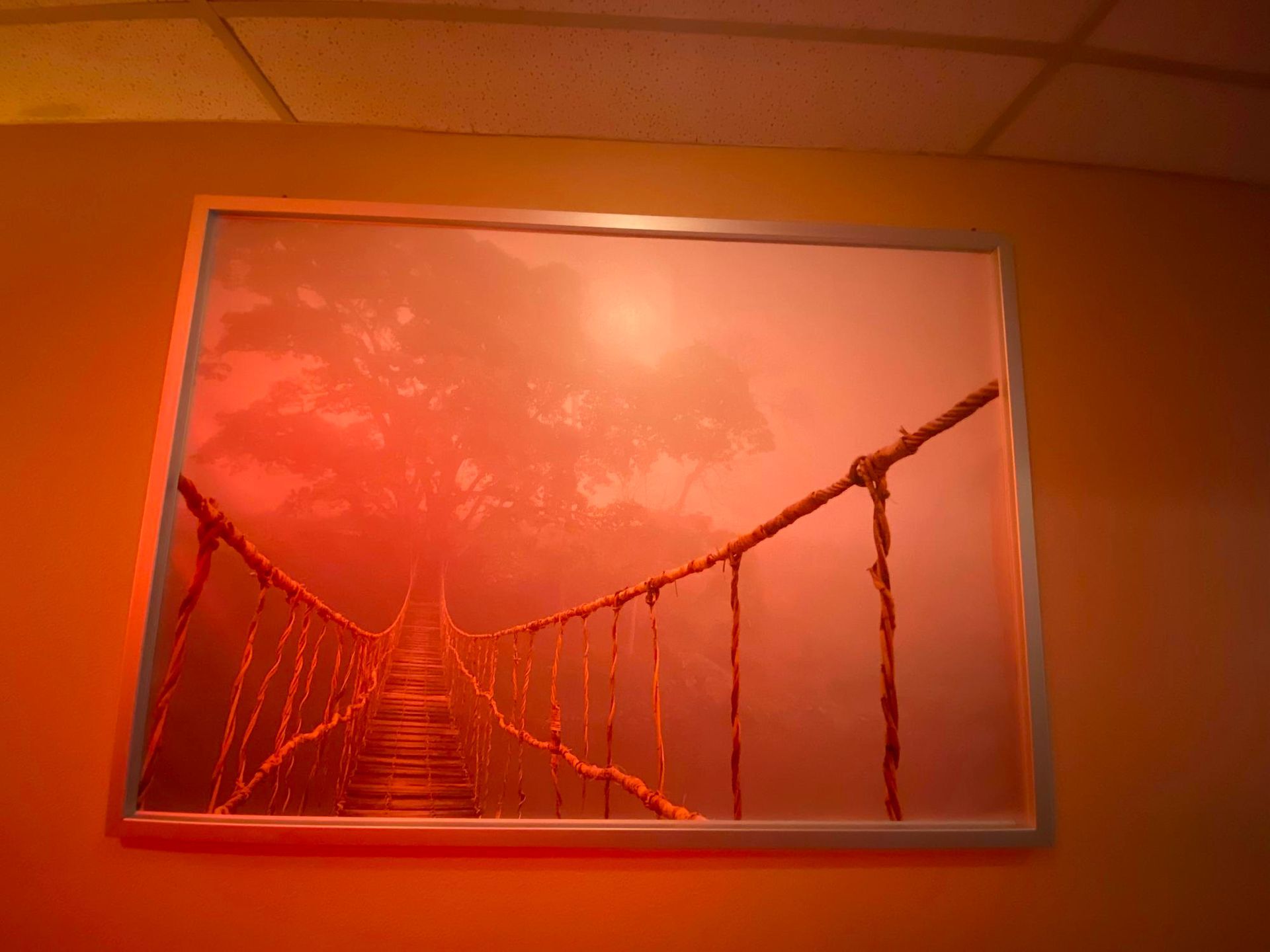 Framed sunset photo of a suspension bridge over water, glowing in warm orange light