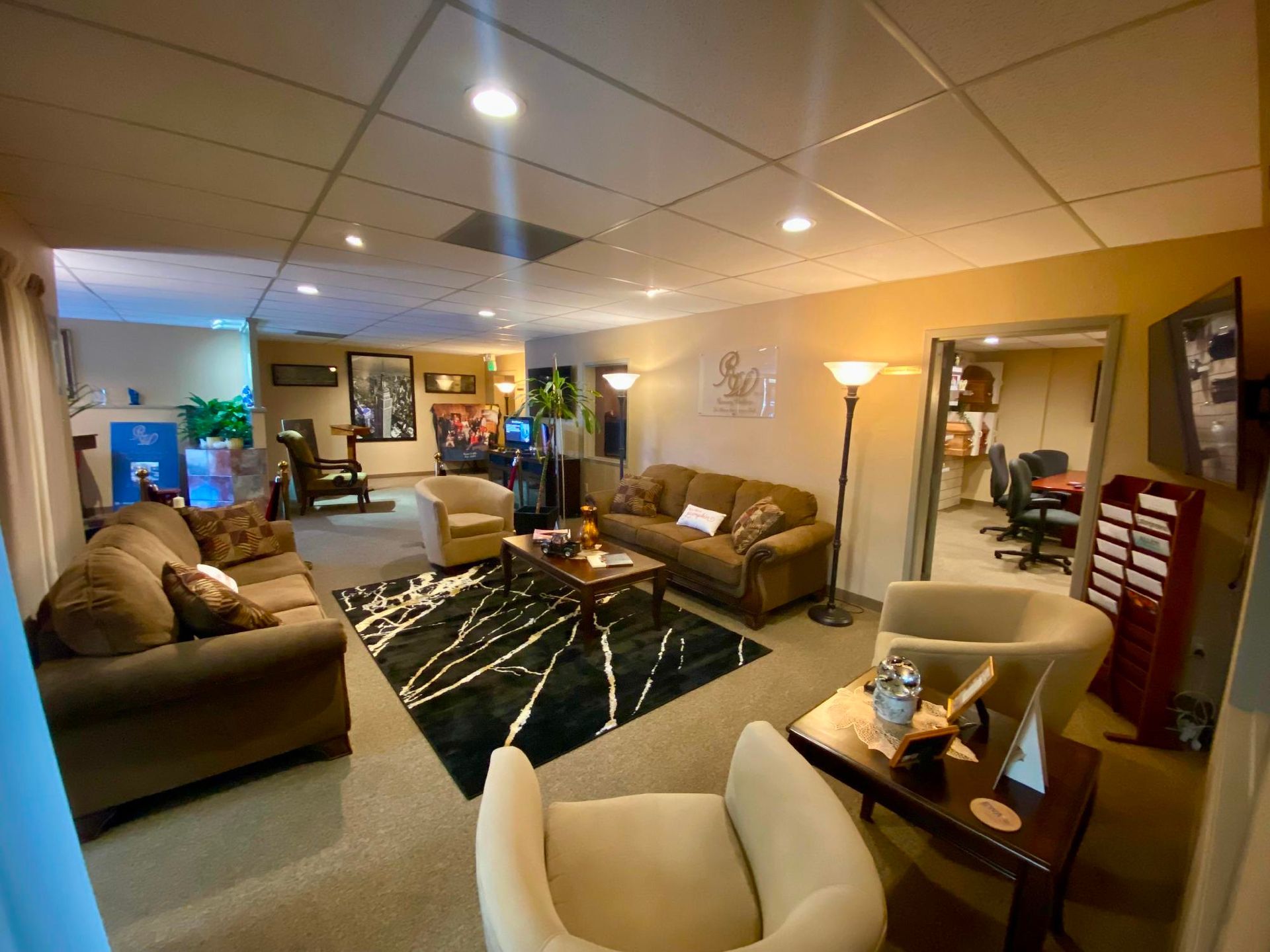 Spacious living room with sofas, armchairs, a black rug, floor lamp, and warm recessed lighting