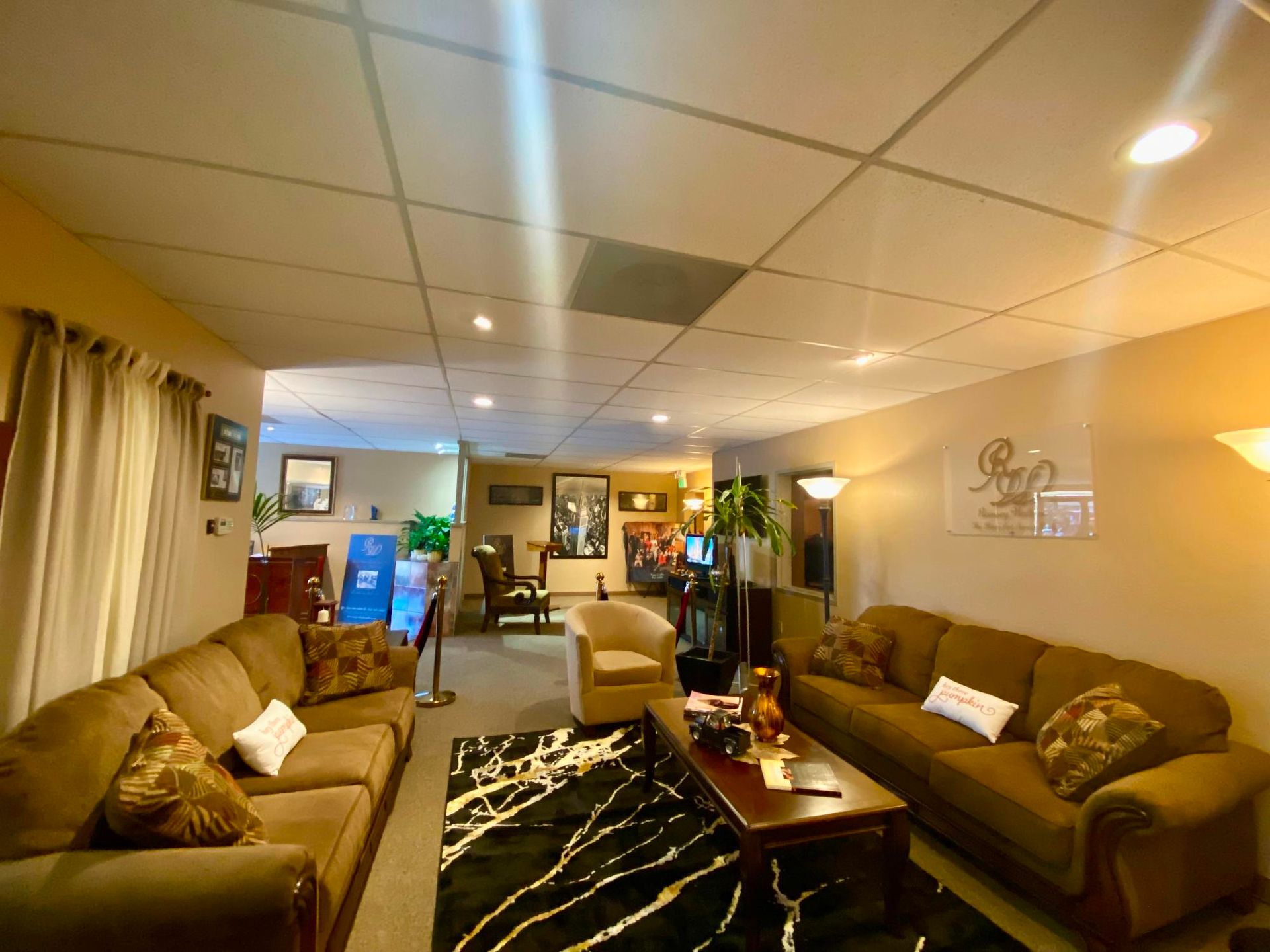 Cozy living room with tan sofas, coffee table, patterned rug, and recessed ceiling lights.