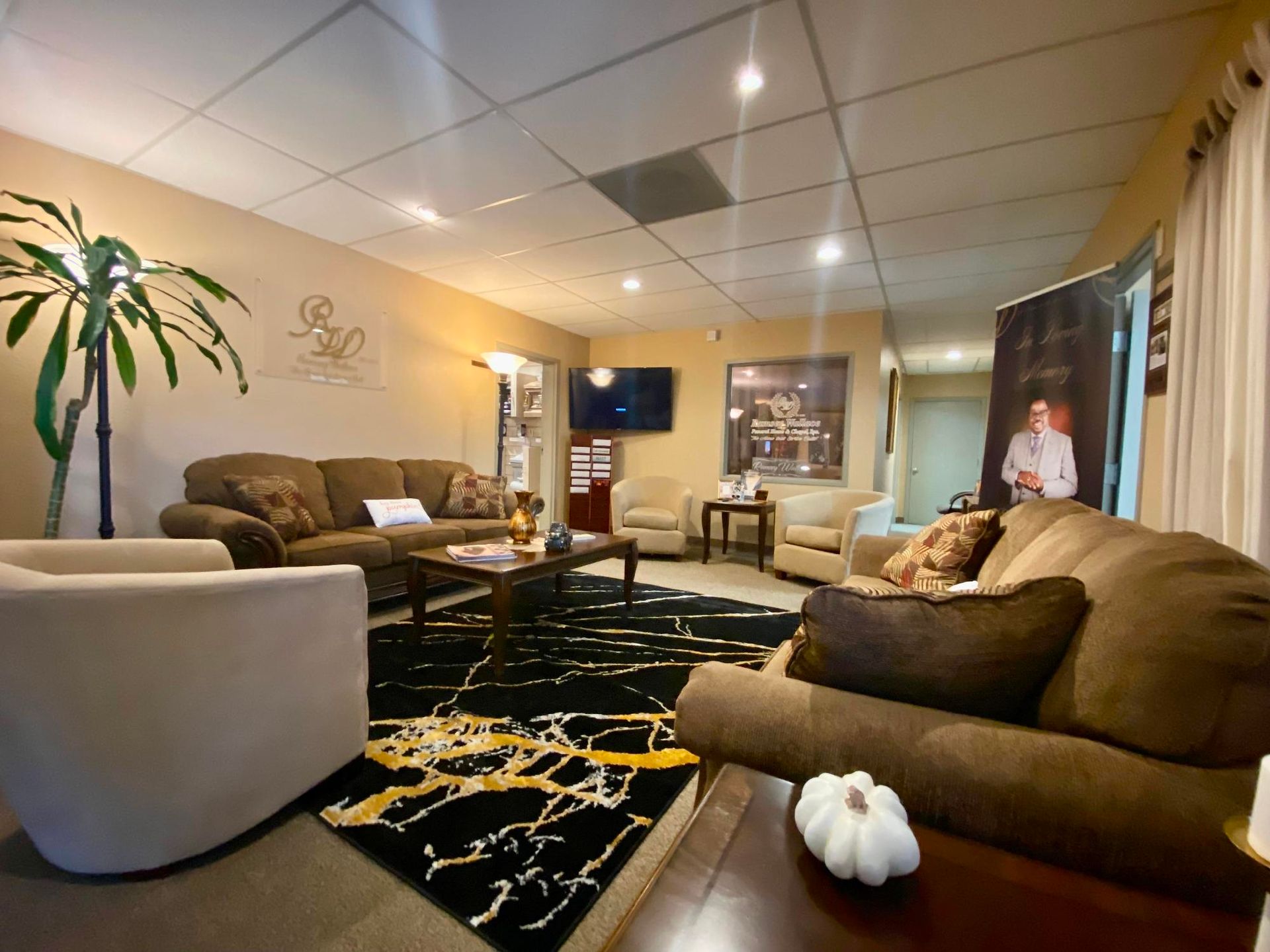 Cozy living room with brown sofas, white chair, black rug, and recessed ceiling lights
