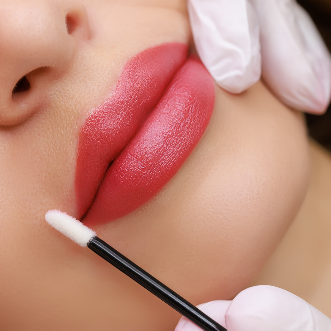 Einer Frau werden die Lippen mit rosa Lippenstift bemalt.