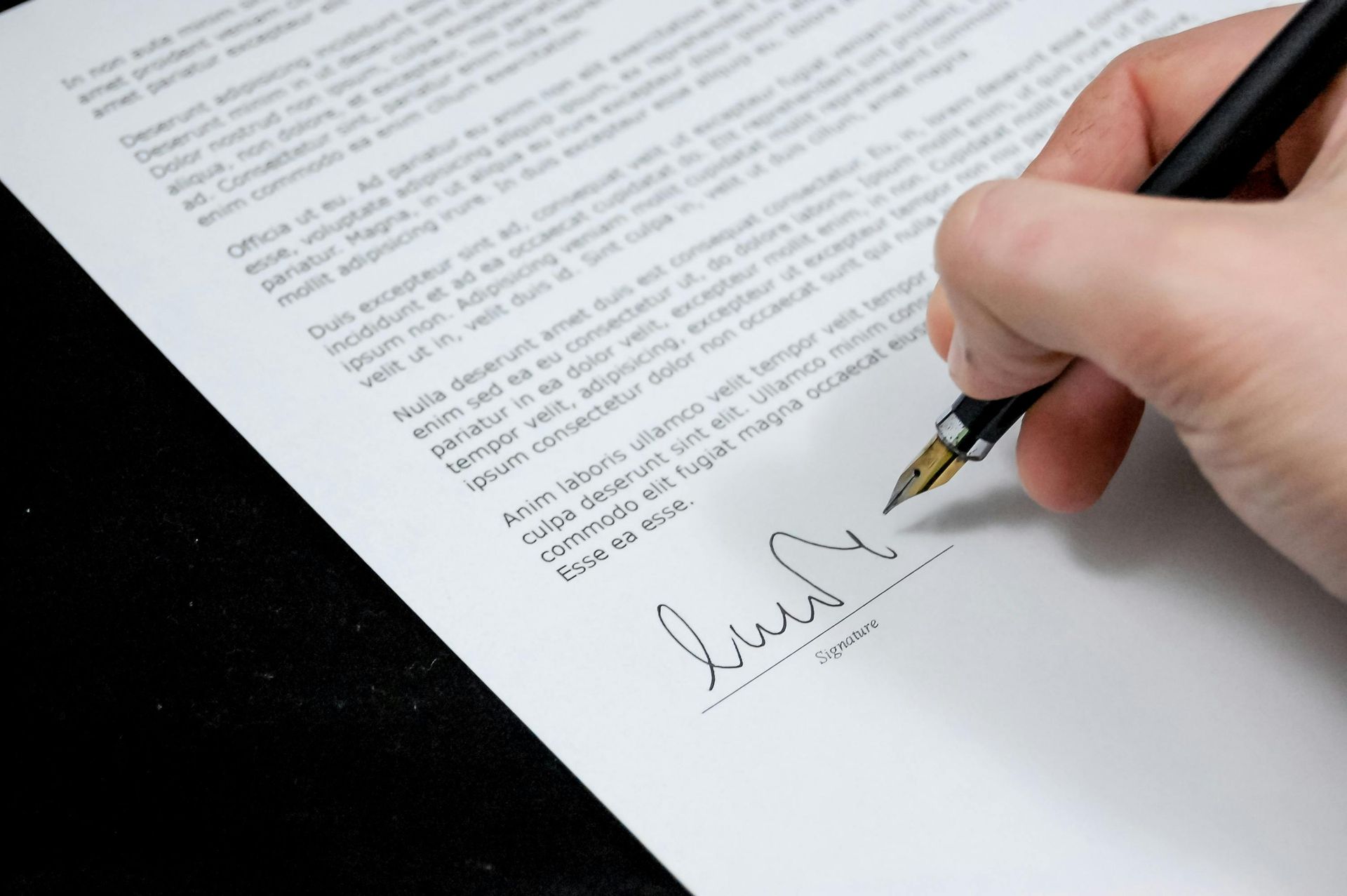 A hand with a pen signing a document.