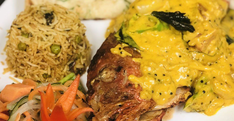 Plate of food: Fried fish with yellow sauce, rice, salad, and a side of white food.