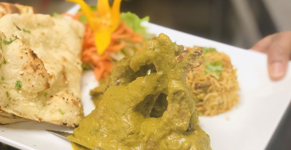 Plate of Indian food: naan bread, curry, rice, and garnish.